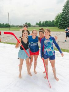 Four women and girls pose for a photo with hockey sticks while playing games at Momentum Youth Conference.